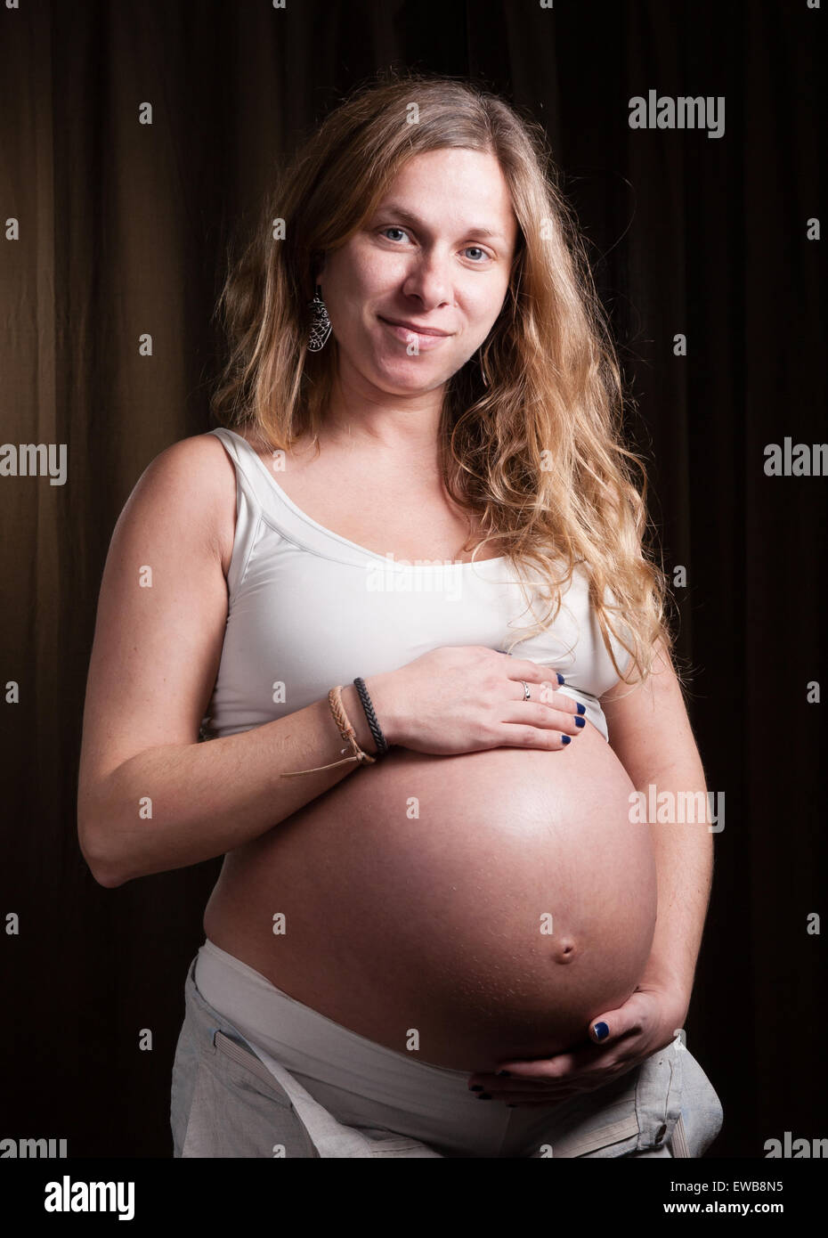 Bionda donna incinta guardando la fotocamera in un ritratto in studio Foto Stock