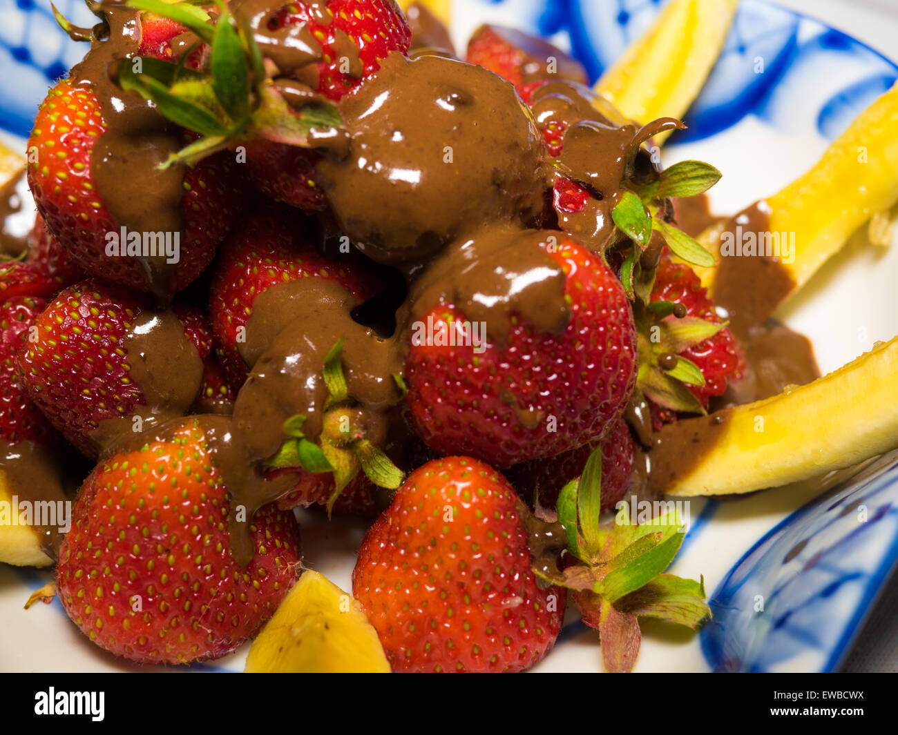 Banana e fragola sotto hot chodolate sulla tradizionale russo piastra - gzhel Foto Stock