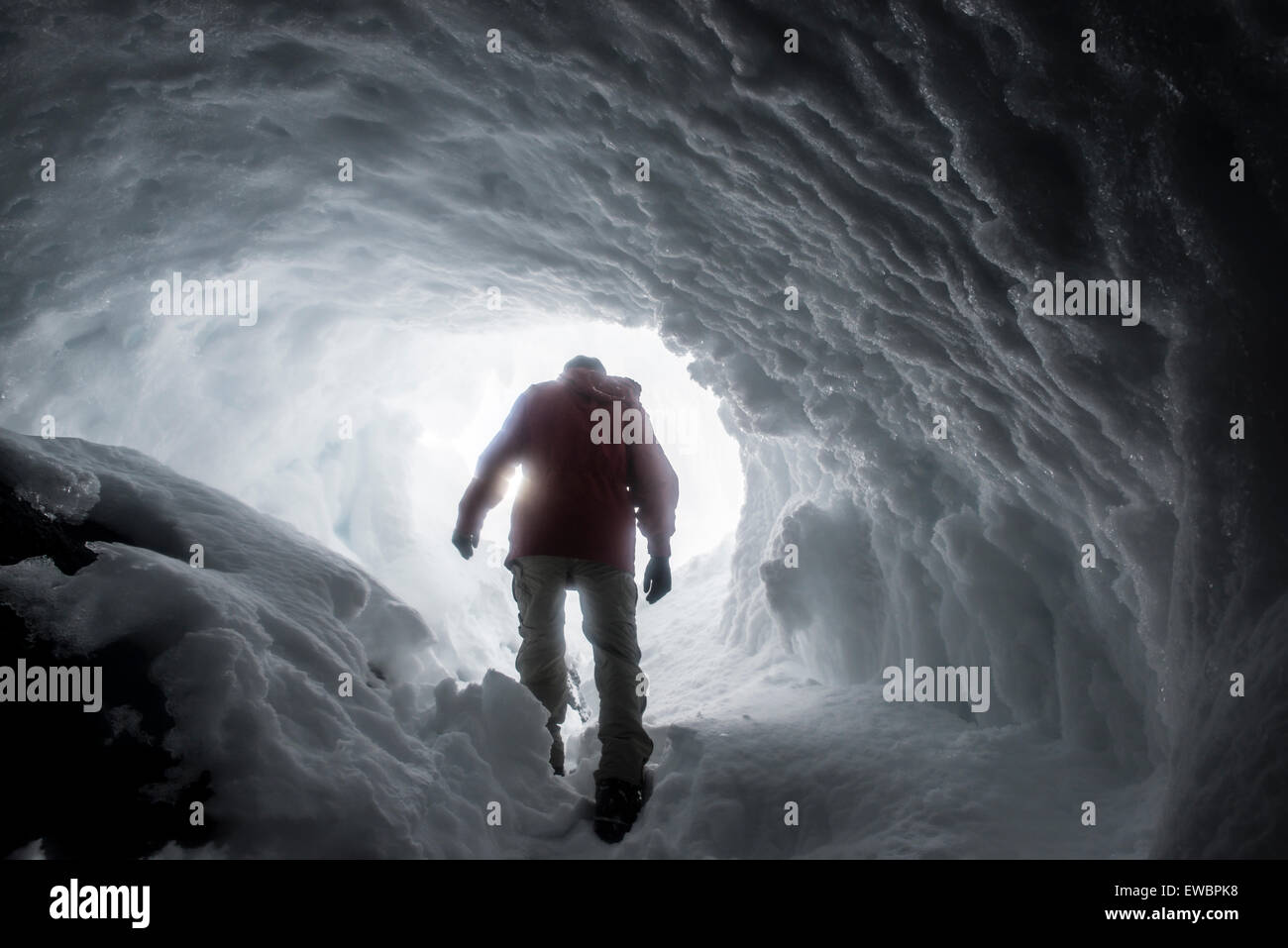 Un uomo cammina verso l'uscita di una grotta di vapore vicino alla vetta del Monte Erebus, Antartide. Foto Stock