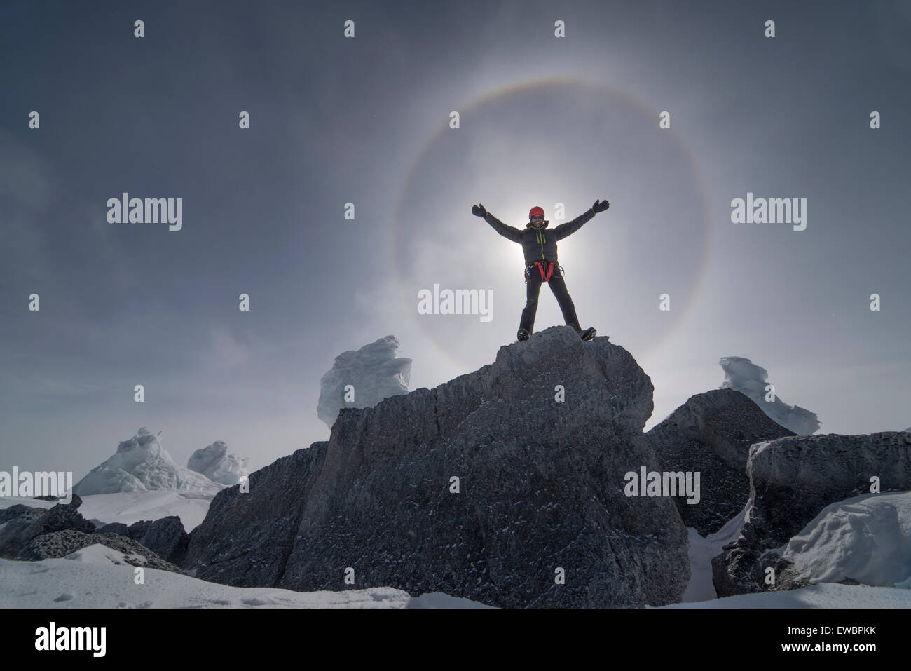 Un uomo si erge di fronte al sole che si produce un grande alone da cristalli di ghiaccio nel cielo. Foto Stock