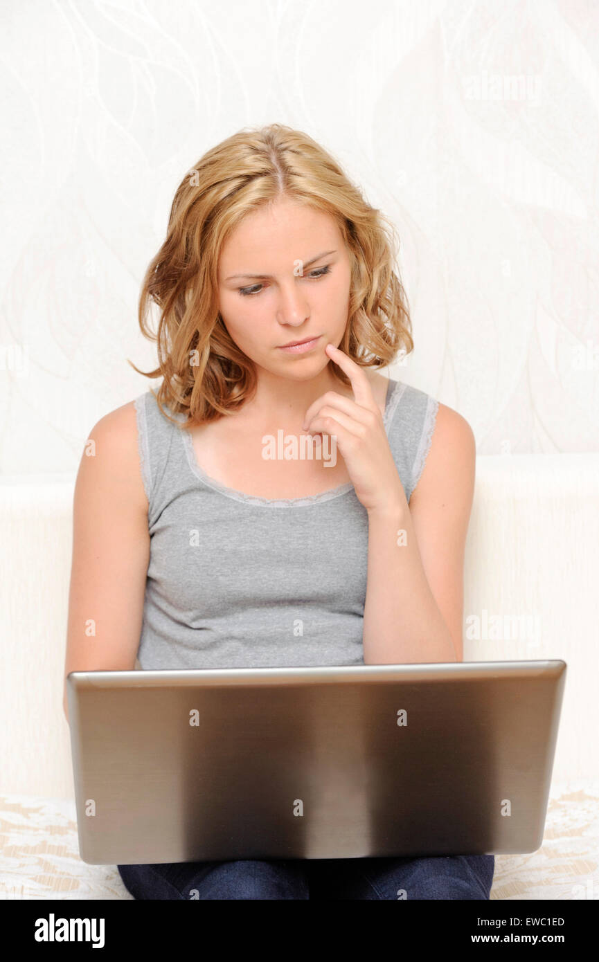 Considerato giovane donna seduta con il computer portatile Foto Stock