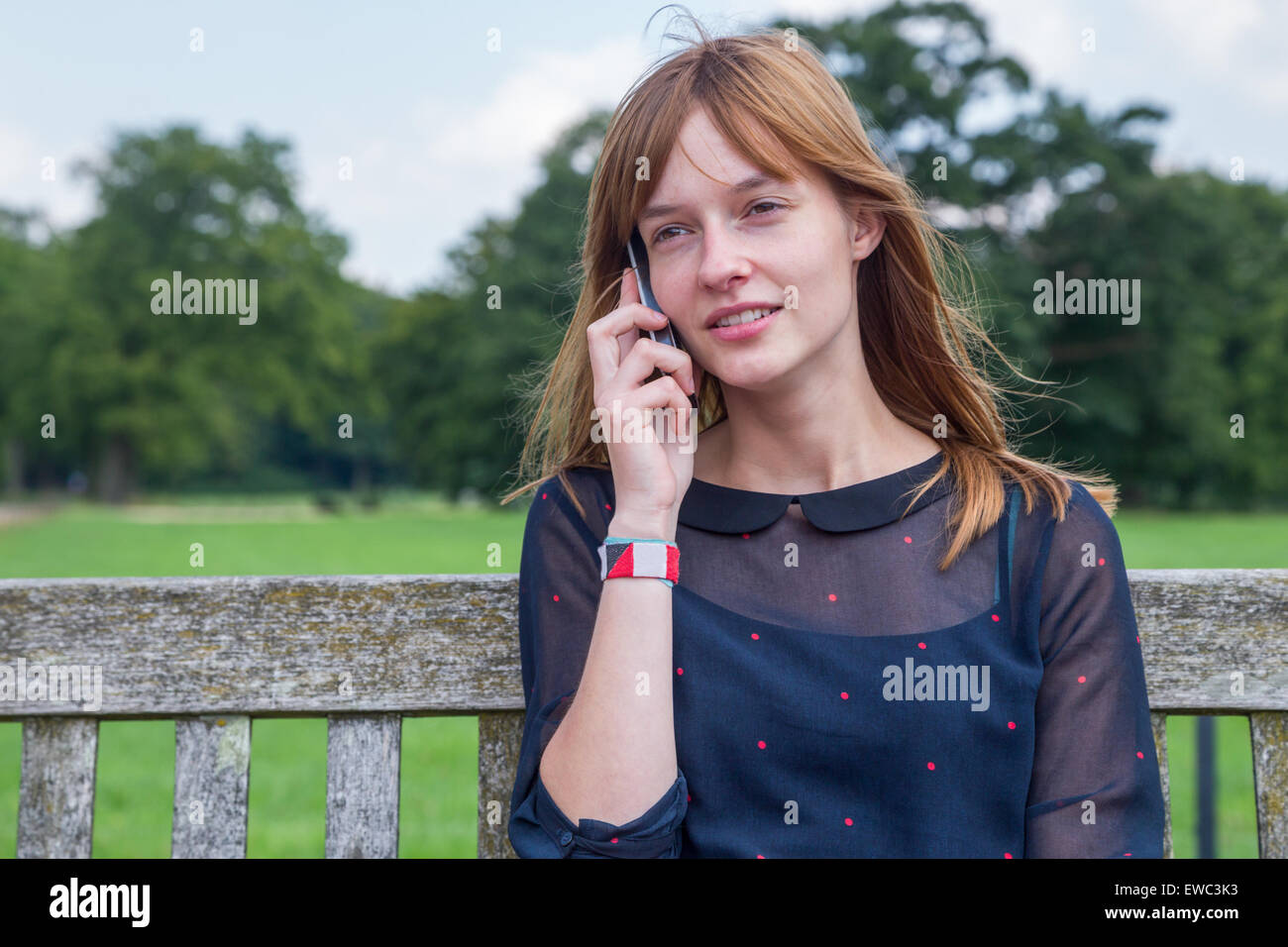 Caucasian ragazza con i capelli rossi telefonare con il cellulare in natura Foto Stock