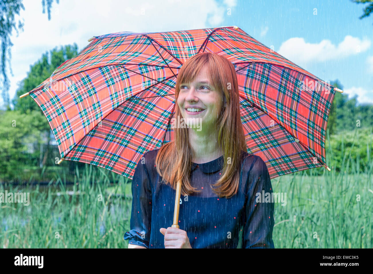 Caucasian ragazza adolescente holding ombrello sul giorno di pioggia nel verde della natura Foto Stock