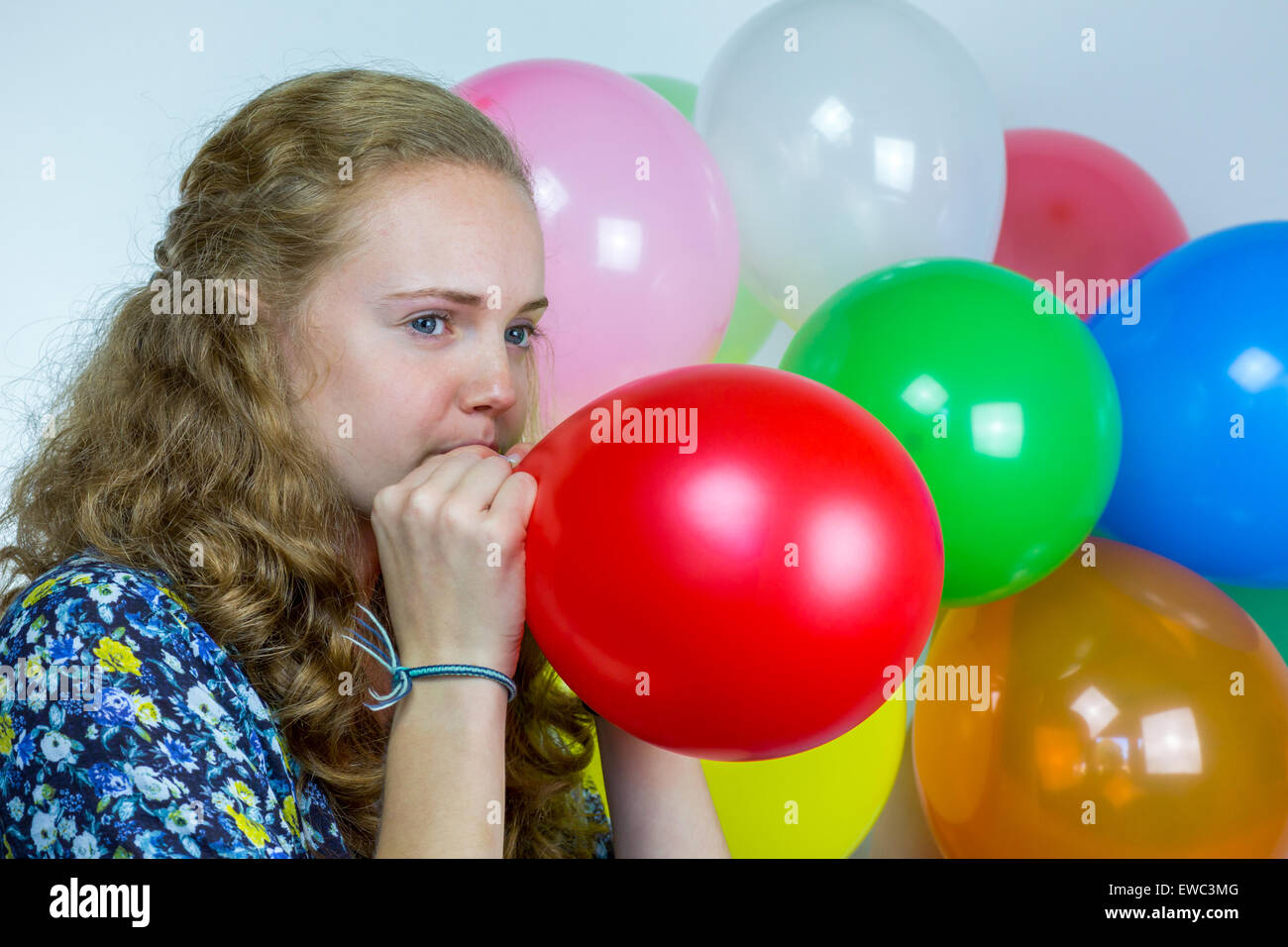 Dutch ragazza adolescente soffiando il gonfiaggio di palloncini colorati per la festa di compleanno Foto Stock