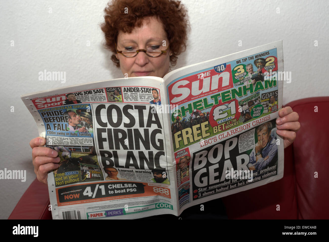 Donna leggendo una copia del giornale di Sun (11.03.2015) Foto Stock