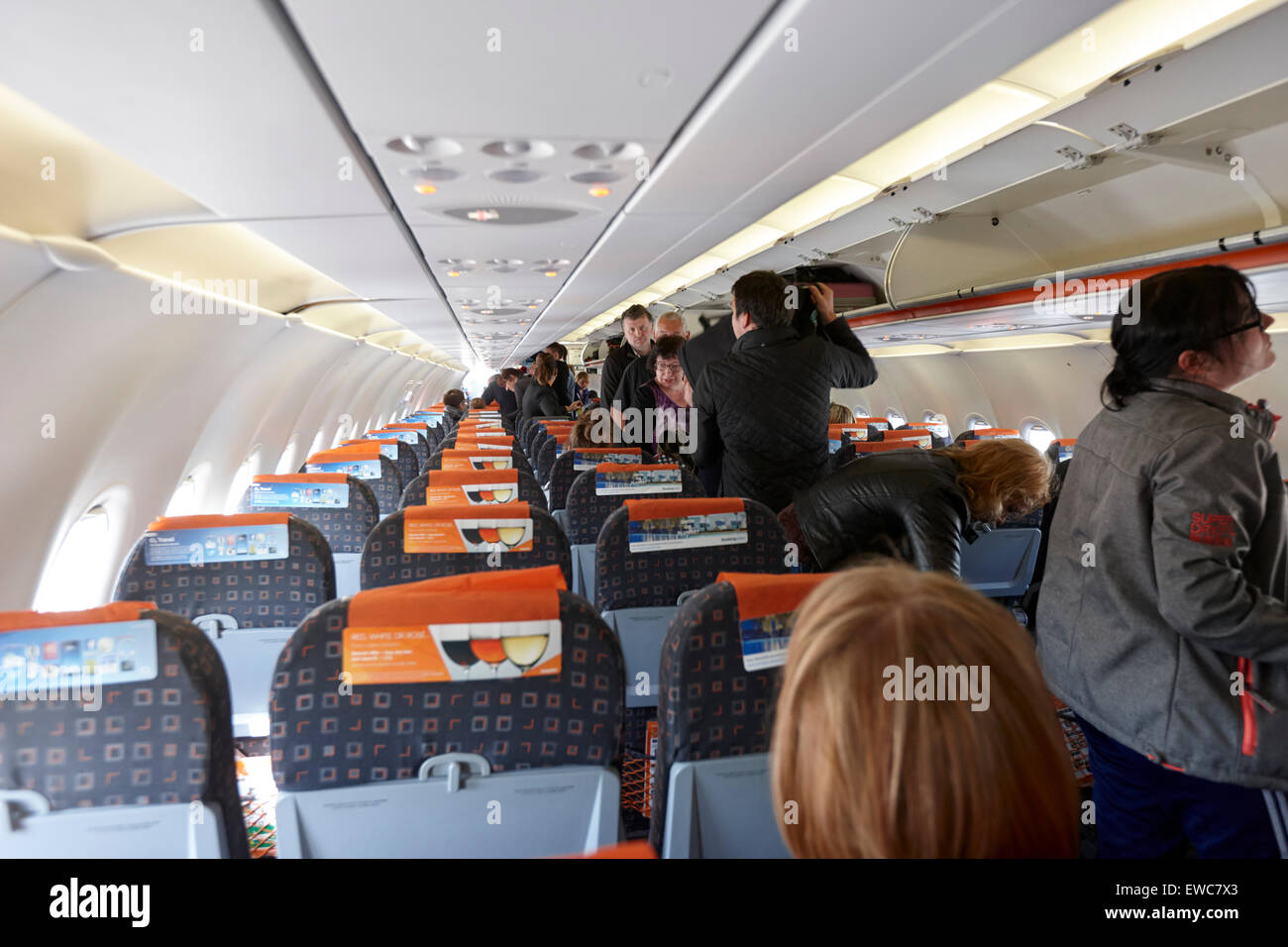 Passeggeri posto per i bagagli a mano in scompartimenti sopraelevati sul volo Easyjet subisca l'Aeroporto Internazionale di Belfast Regno Unito Foto Stock