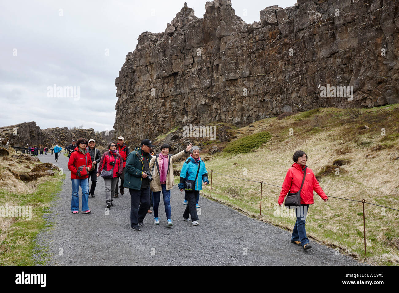 Turisti asiatici a piedi attraverso il Almannagja linea anomalia nel mid-atlantic ridge Nord America placca Thingvellir national park Foto Stock