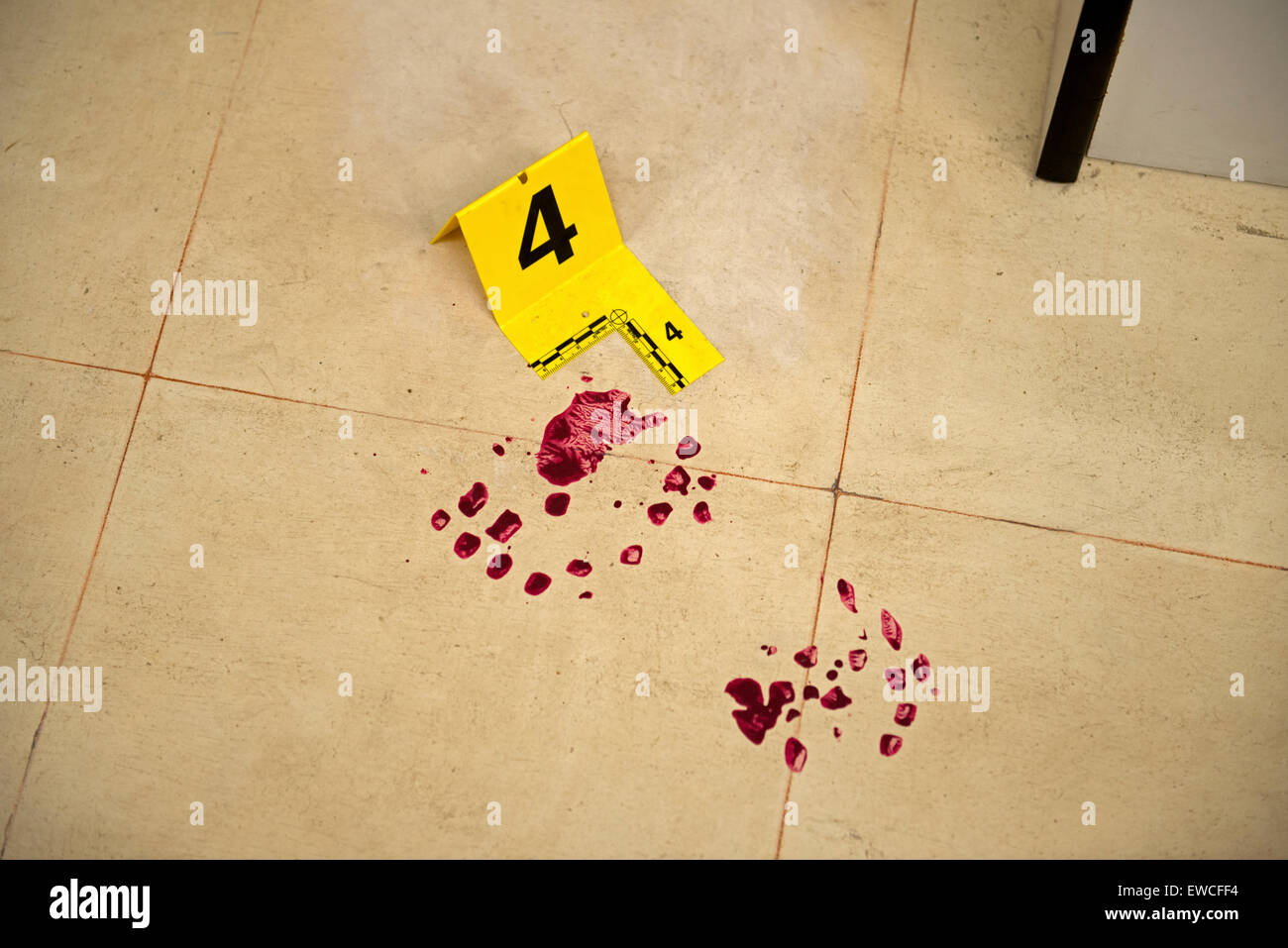 Prove di sangue simulate e un marcatore forense numerato su un pavimento di piastrelle in una scena del crimine simulata utilizzata per l'addestramento investigativo forense. Foto Stock