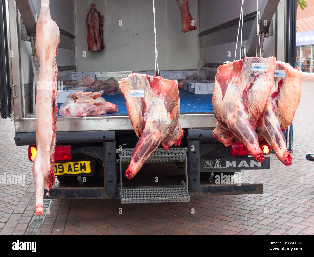 Delle carni suine e bovine carcasse di bestiame su un camion per essere scaricato presso un negozio di macellaio. Foto Stock