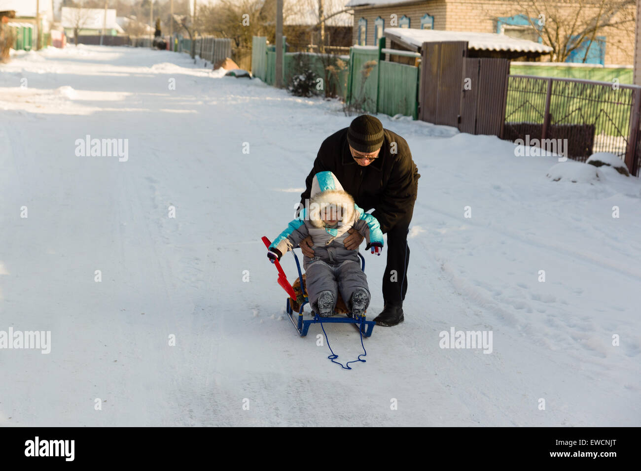 Cordialmente vestito in tuta boy con il nonno a giocare in strada nevoso inverno Foto Stock