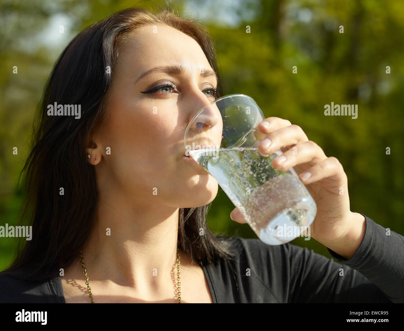 Donna con un bicchiere di acqua frizzante e soleggiata giornata estiva Foto Stock