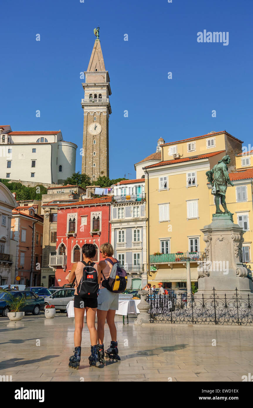 I turisti sulle lame a rullo a Tartini piazza con la statua di Giuseppe Tartini con la chiesa di San Giorgio dietro. Pirano. Foto Stock