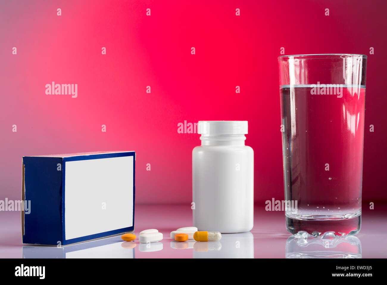 Varie pillole,BOX,bottiglia e bicchiere di acqua su sfondo colorato Foto Stock