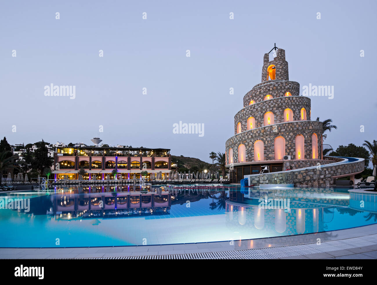 Crepuscolo presso la Bodrum Imperial hotel nella regione di Akyarlar della Turchia con la piscina principale e scivolo d'acqua in primo piano. Foto Stock