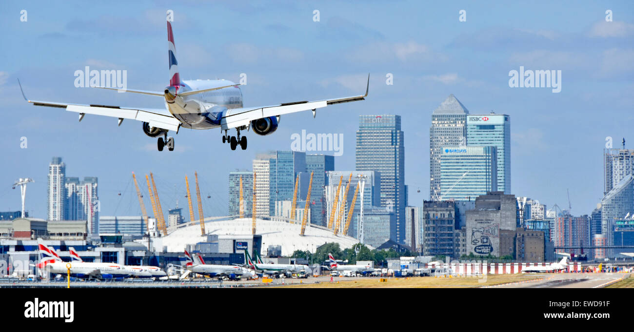 Volo British Airways in atterraggio a London City Airport (Newham) con l'O2 Arena e Canary Wharf (Tower Hamlets) skyline al di là Foto Stock