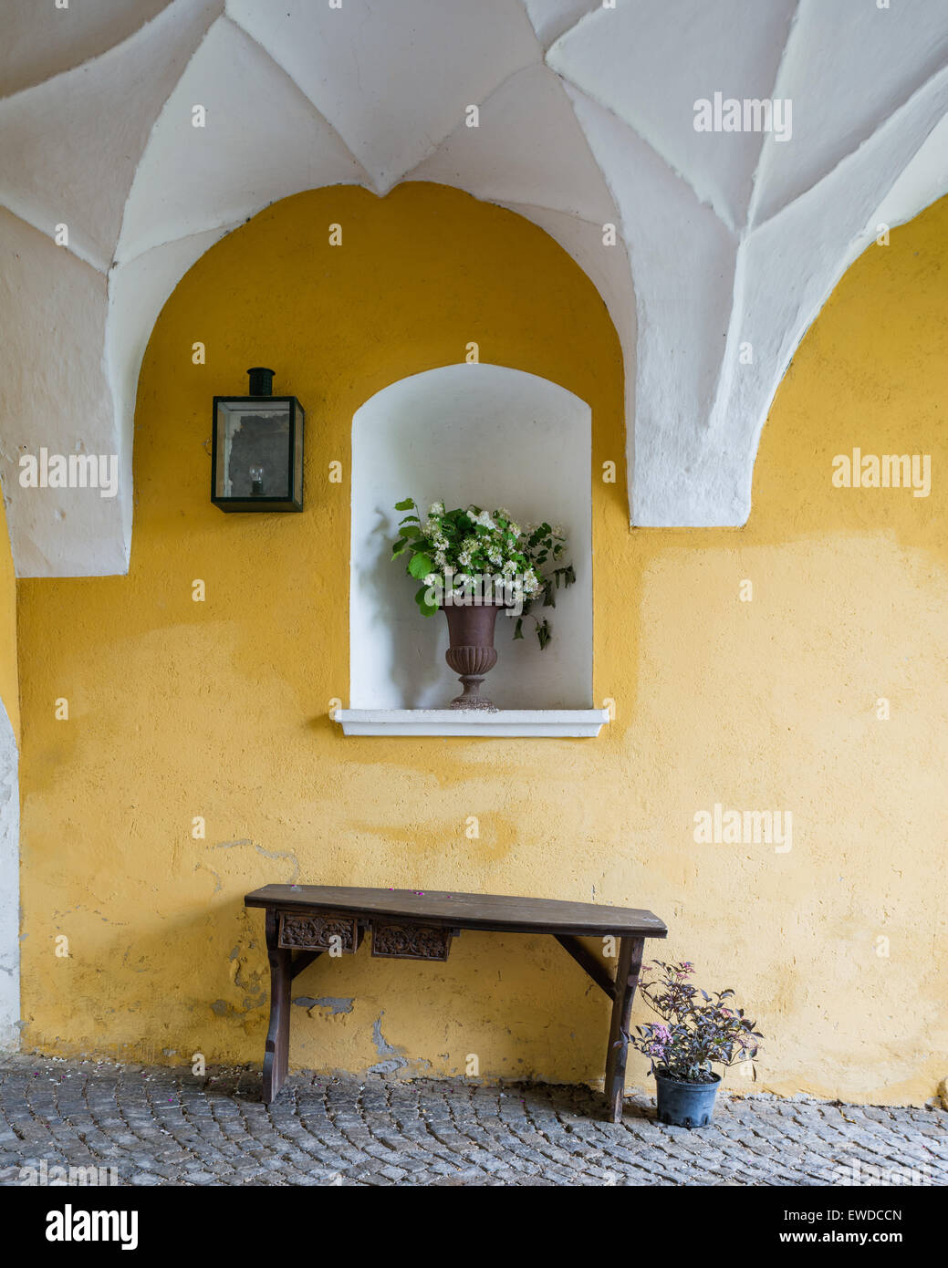 Panca di legno giallo contro il muro di pietra nell'arco di entrata con soffitto a volta Foto Stock