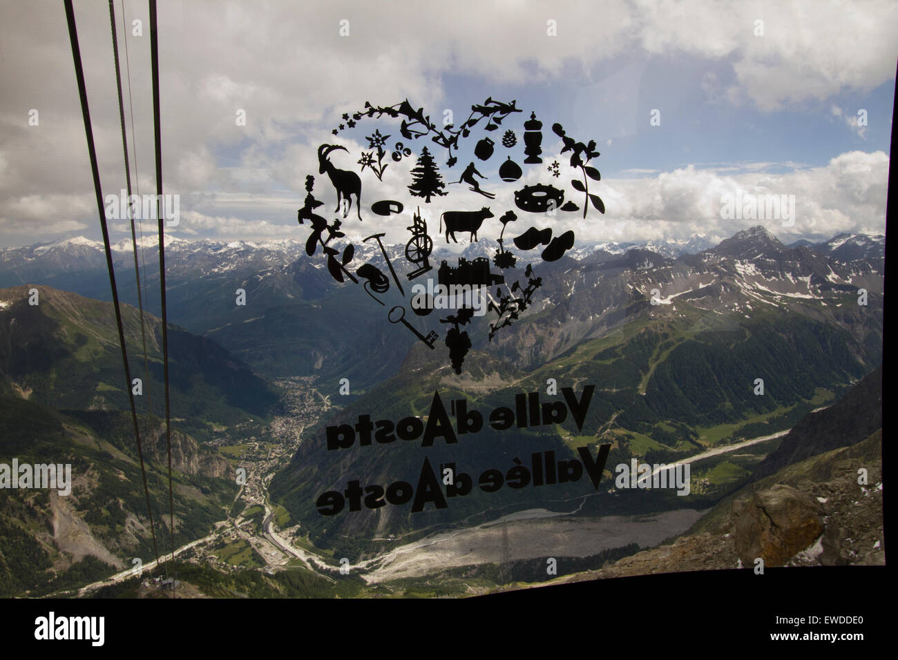 Courmayeur, Italia, 23 giugno 2015. Una valle d'Aosta logo sulla finestra della funivia gondola si sovrappone la Valle d'Aosta paesaggio. Il nuovo Skyway funivia che collega la città di Courmayeur a Punta Helbronner (3,466 m) nel massiccio del Monte Bianco. Foto Stock