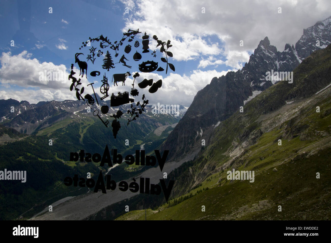 Courmayeur, Italia, 23 giugno 2015. Una valle d'Aosta logo sulla finestra della funivia gondola si sovrappone la Val Veny paesaggio. Il nuovo Skyway funivia che collega la città di Courmayeur a Punta Helbronner (3,466 m) nel massiccio del Monte Bianco. Foto Stock