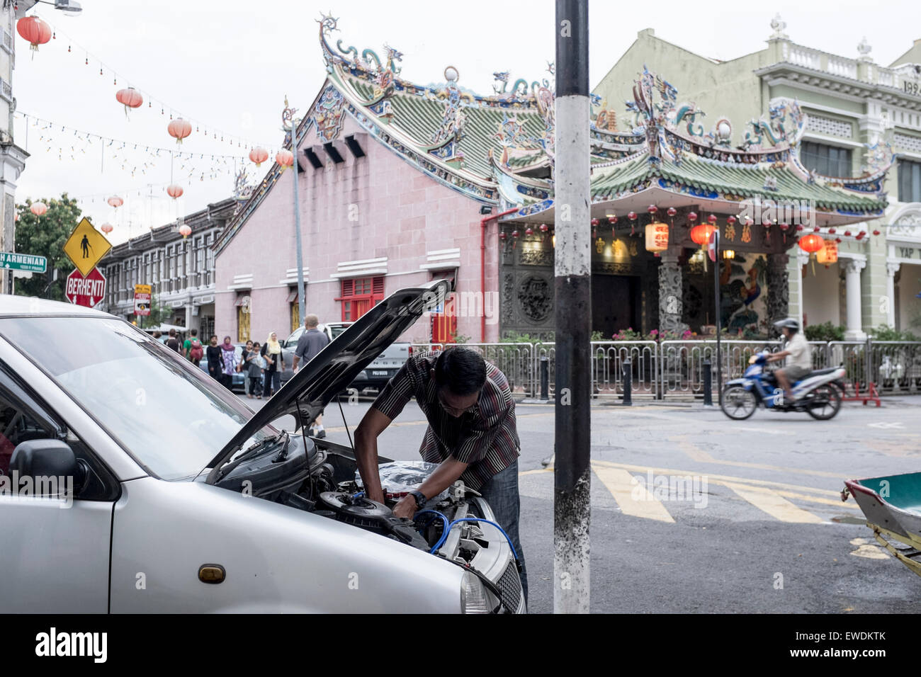 Un uomo che ripara la sua auto in font di Yap Kongsi tempio di Georgetown, Penang, Malaysia Foto Stock