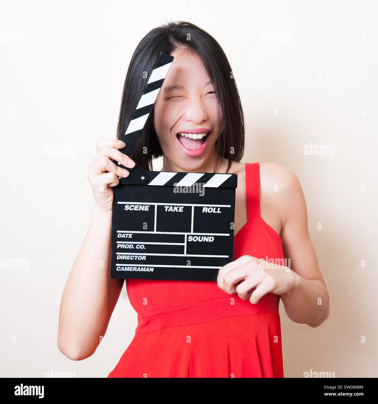 Funny bella donna asiatica con abito rosso e movie clapperboard su sfondo bianco Foto Stock