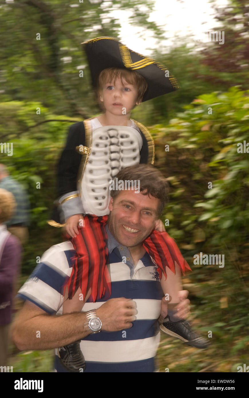 Padre che porta il suo figlio sulle sue spalle durante una comunità locale estate parade, Frensham, Surrey, Regno Unito. Foto Stock