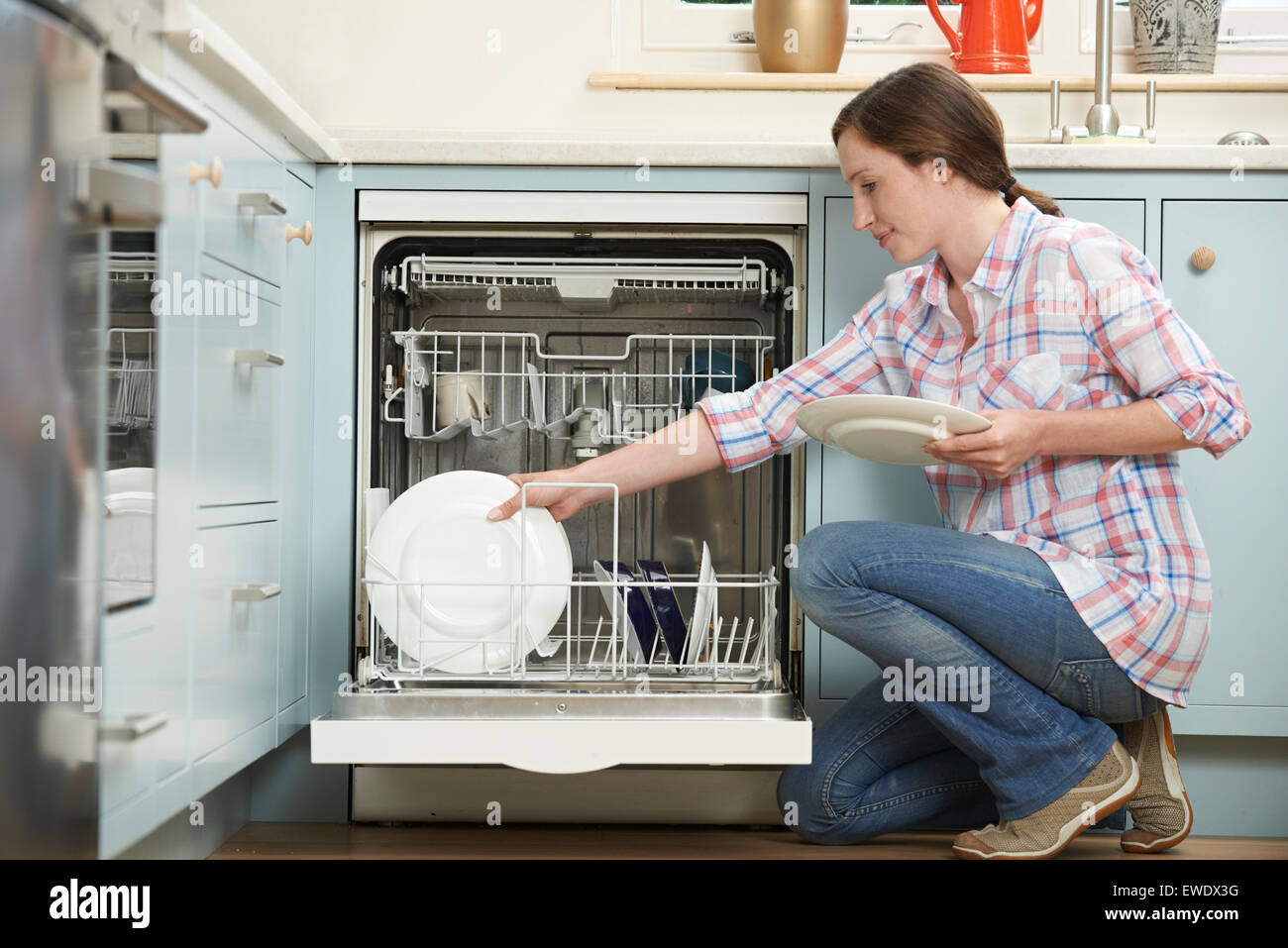Donna caricamento di lavastoviglie in cucina Foto Stock