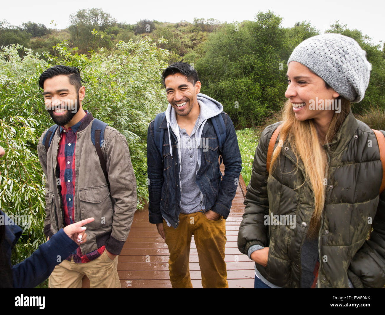 Sorridente giovane donna e due giovani uomini a camminare in un parco Foto Stock