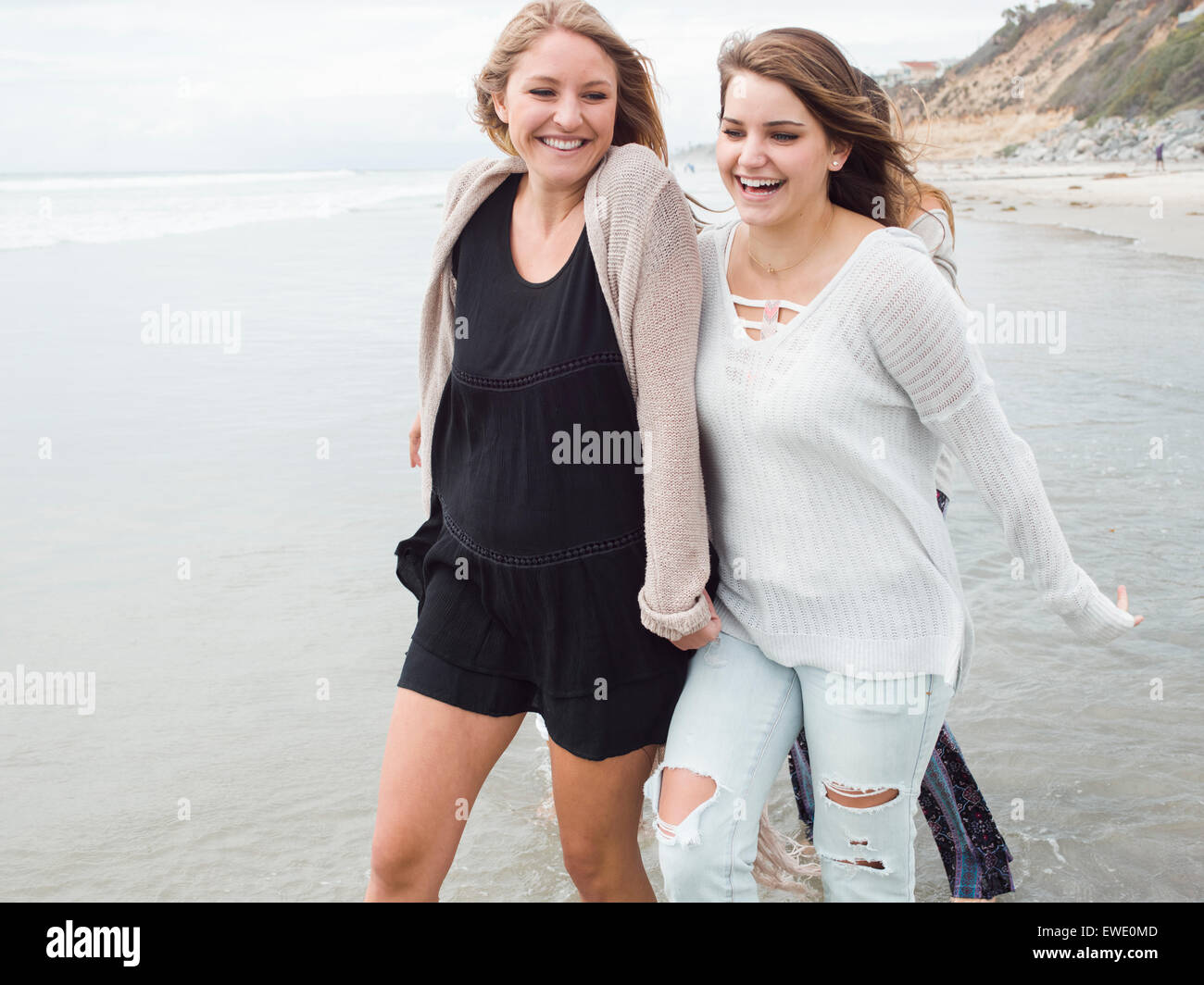Sorridente due giovani donne a camminare su una spiaggia Foto Stock