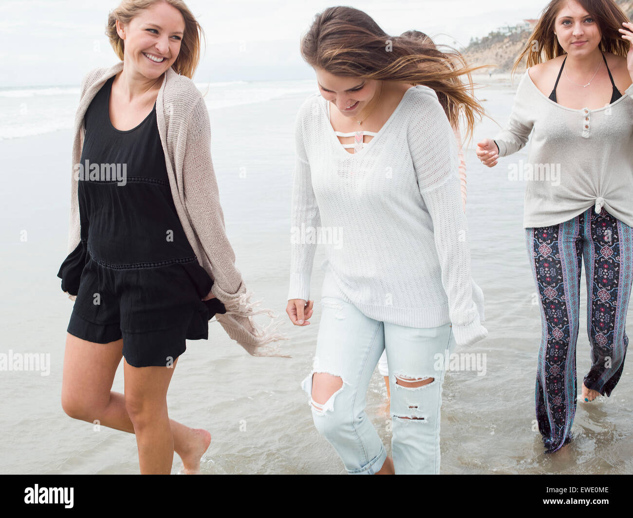 Tre sorridere le giovani donne a camminare su una spiaggia Foto Stock