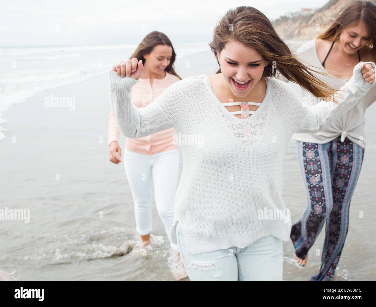 Tre sorridere le giovani donne a camminare su una spiaggia Foto Stock