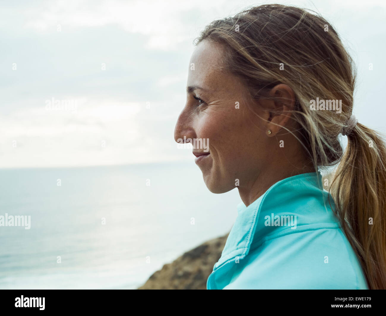 Un sorridente giovane donna, profilo laterale, in un colore blu acceso top Foto Stock