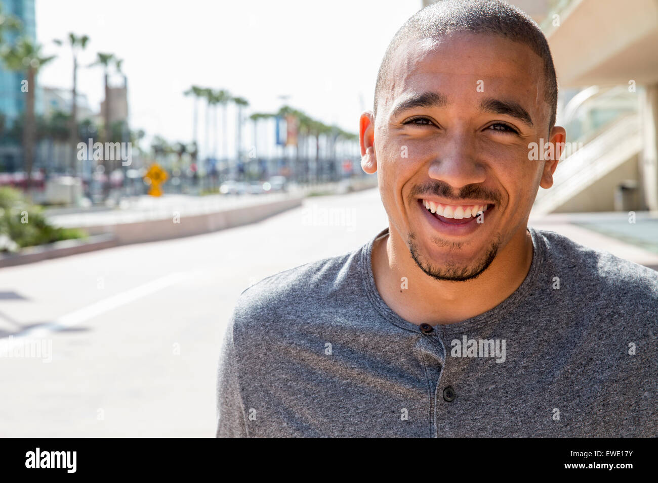 Ritratto di un sorridente giovane uomo in piedi in una strada nella vita della città Foto Stock