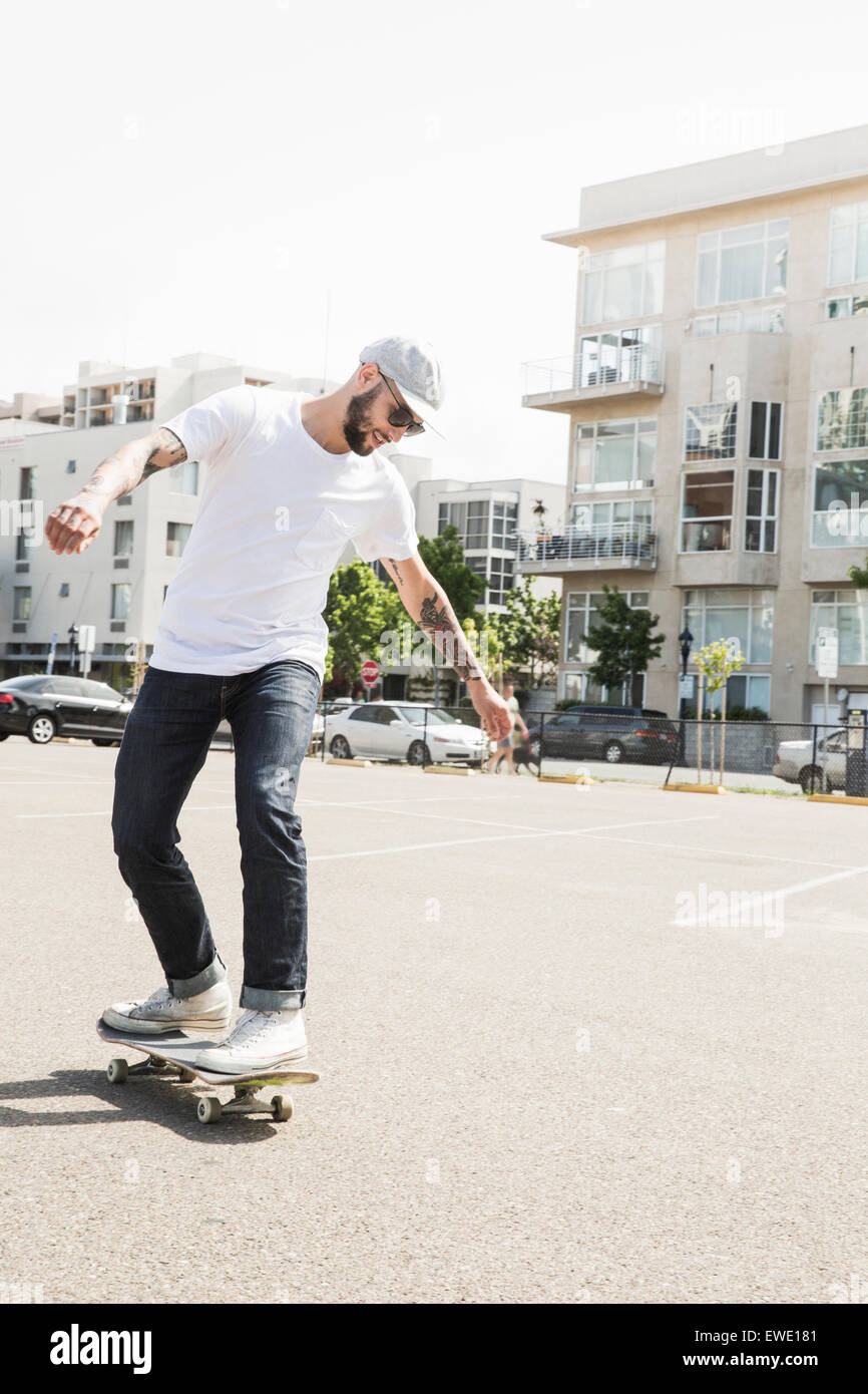 Giovane uomo lo skateboard in un parcheggio urbano per la città la vita Foto Stock