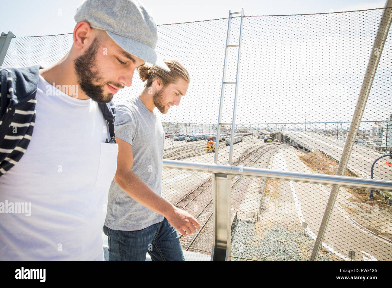 Due giovani uomini a piedi lungo una passerella la vita in città Foto Stock