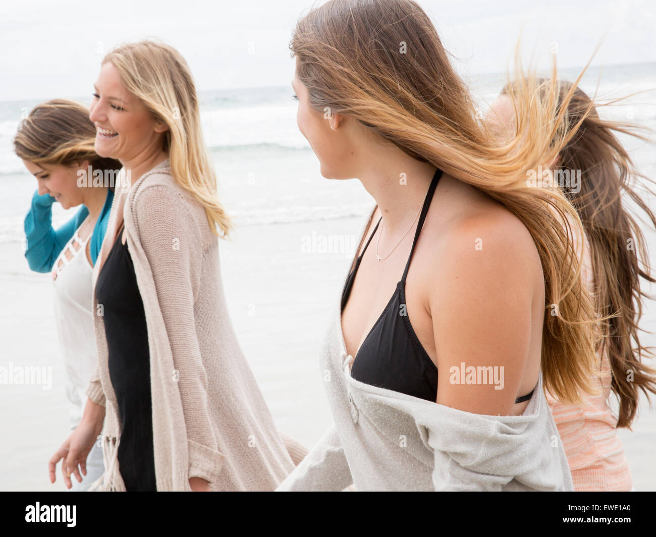Quattro giovani donne a camminare su una spiaggia Foto Stock