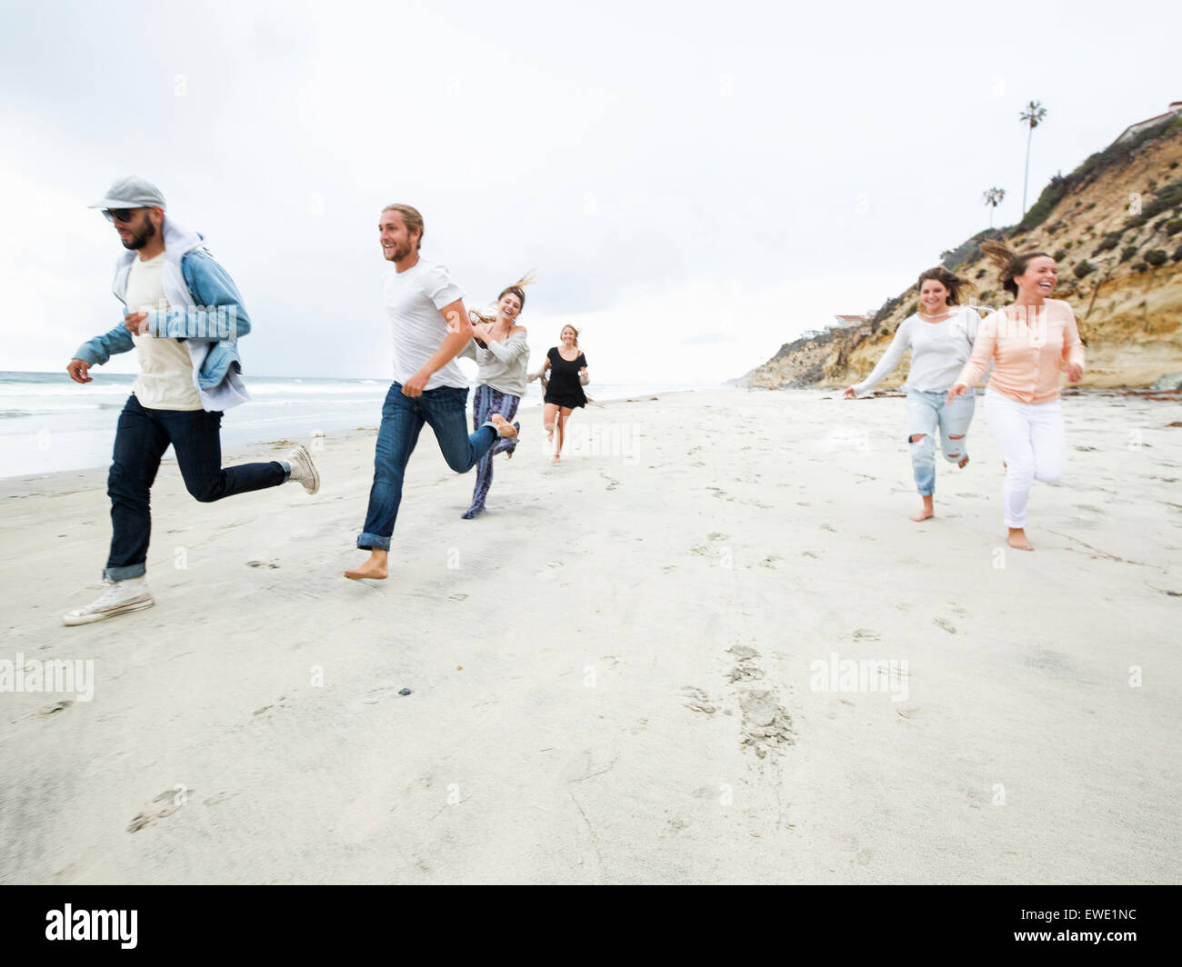 Un gruppo di giovani uomini e donne in esecuzione su una spiaggia, divertimento Foto Stock