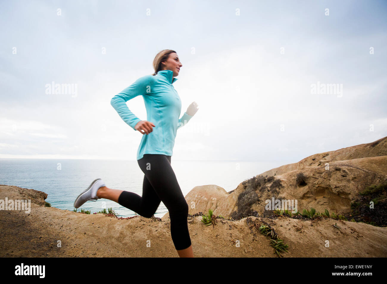 Una giovane donna jogging lungo le falesie costiere usa Foto Stock