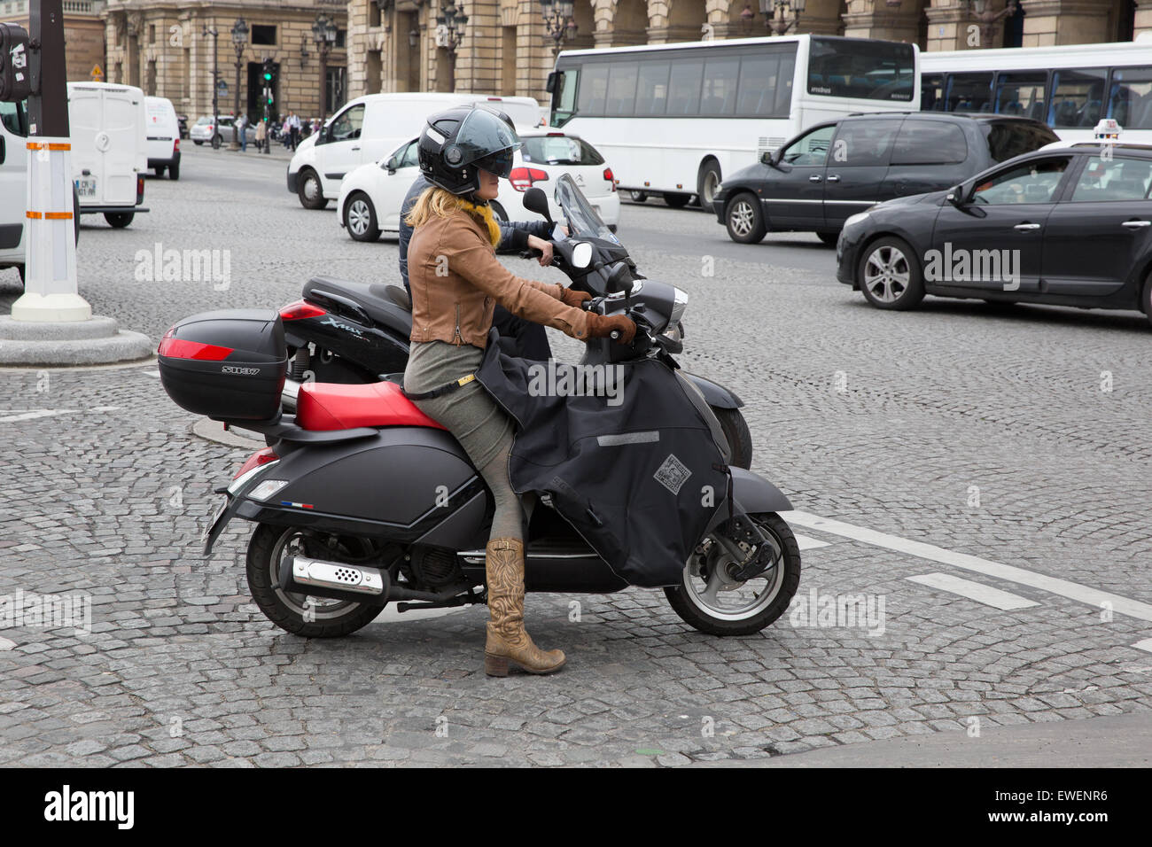La donna in sella a una motocicletta indossare stivali da cowboy e un grembiule protettivo a Parigi, Francia Foto Stock