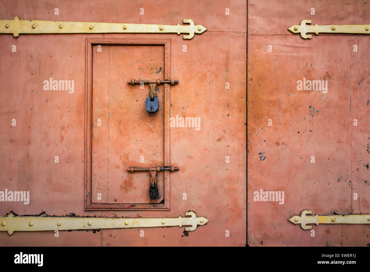 Vecchio lucchetto arrugginito appeso su arancio metallo porta retrò Foto Stock