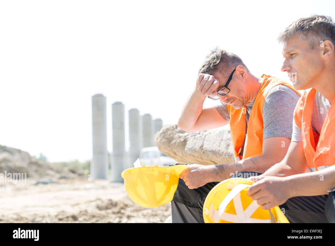 Stanco di supervisor seduta con un collega sul sito in costruzione Foto Stock