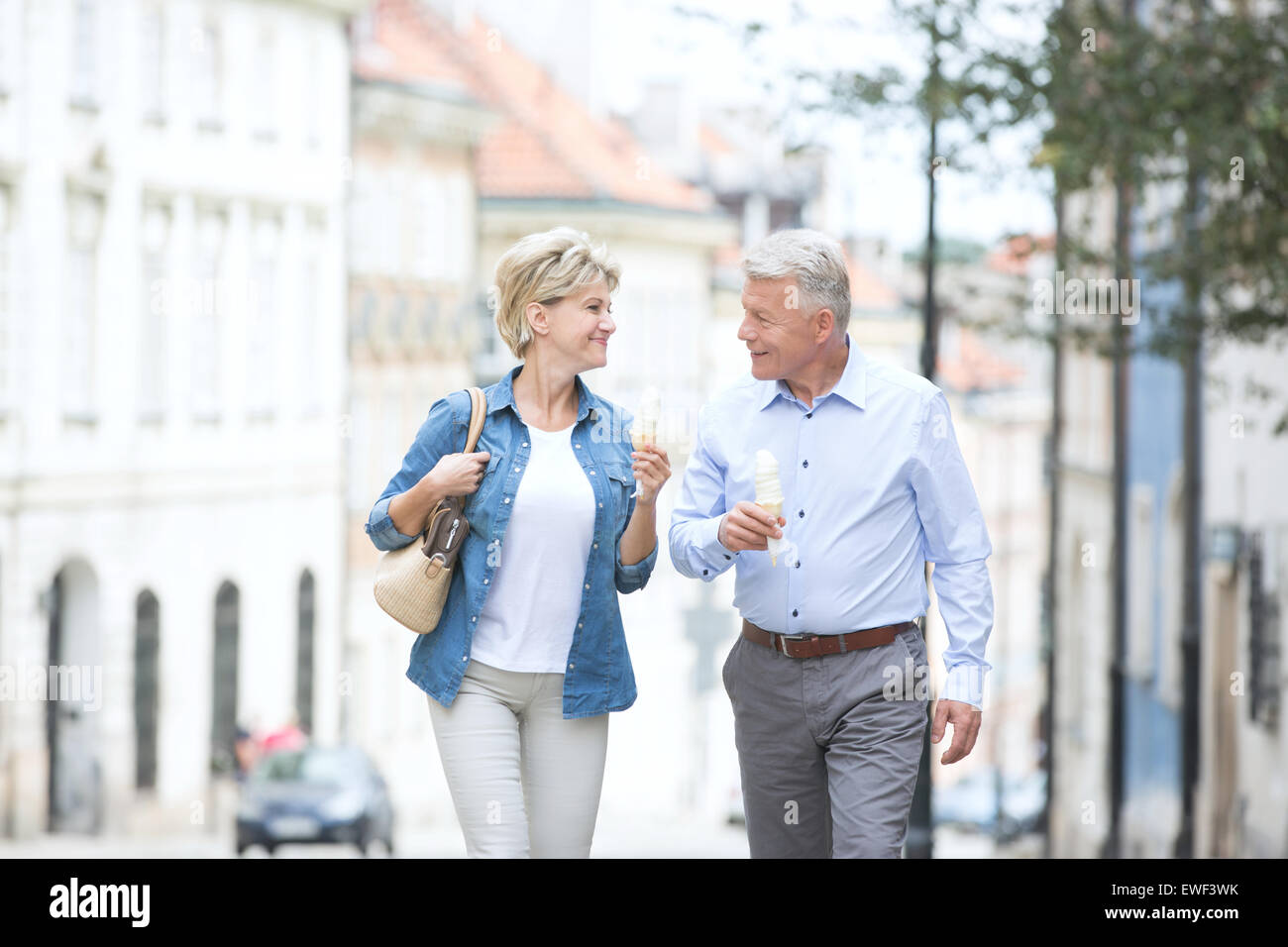Felice di mezza età matura guardando ogni altro tenendo coni gelato in città Foto Stock