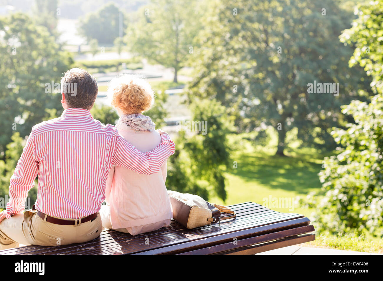 Vista posteriore di mezza età giovane relax su una panchina nel parco Foto Stock