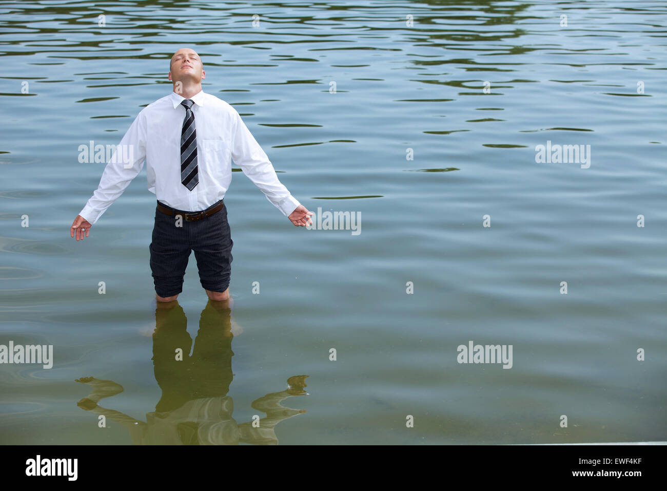 Imprenditore in piedi nel lago a occhi chiusi Foto Stock