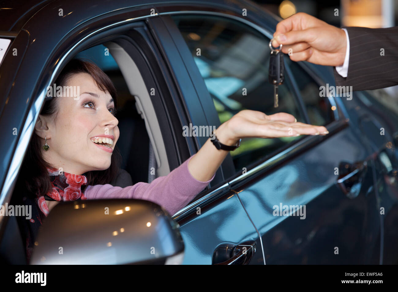 Giovane donna riceve le chiavi della macchina dal venditore auto Foto Stock