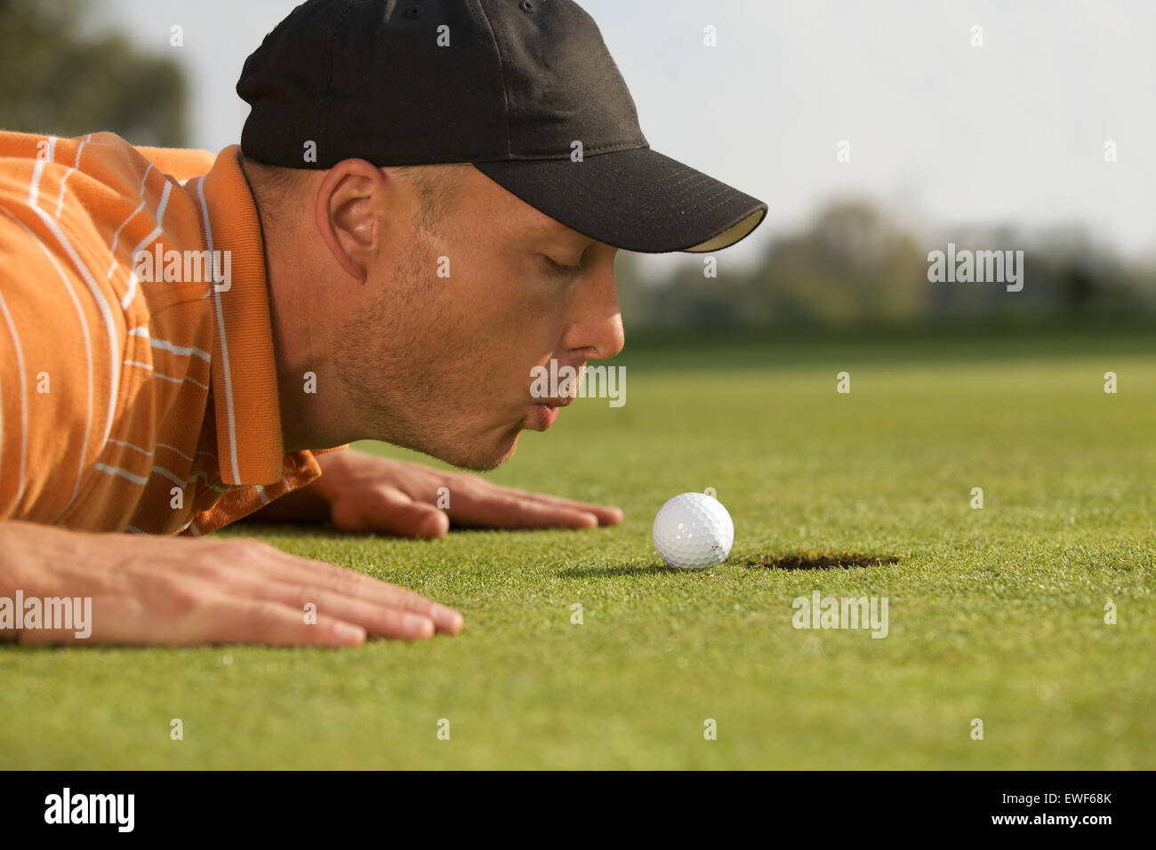Close-up di uomo che soffia sulla pallina da golf Foto Stock