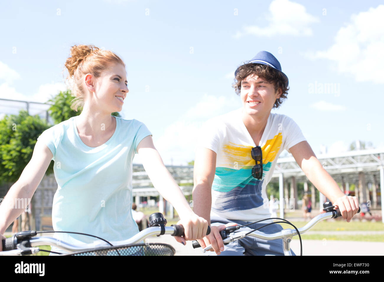 Sorridente giovane guardando gli uni con gli altri mentre escursioni in bicicletta in città Foto Stock