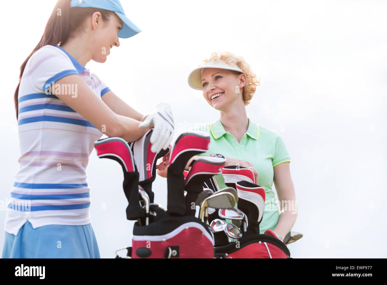 Basso angolo vista di felice golfisti femmina parlando contro il cielo chiaro Foto Stock