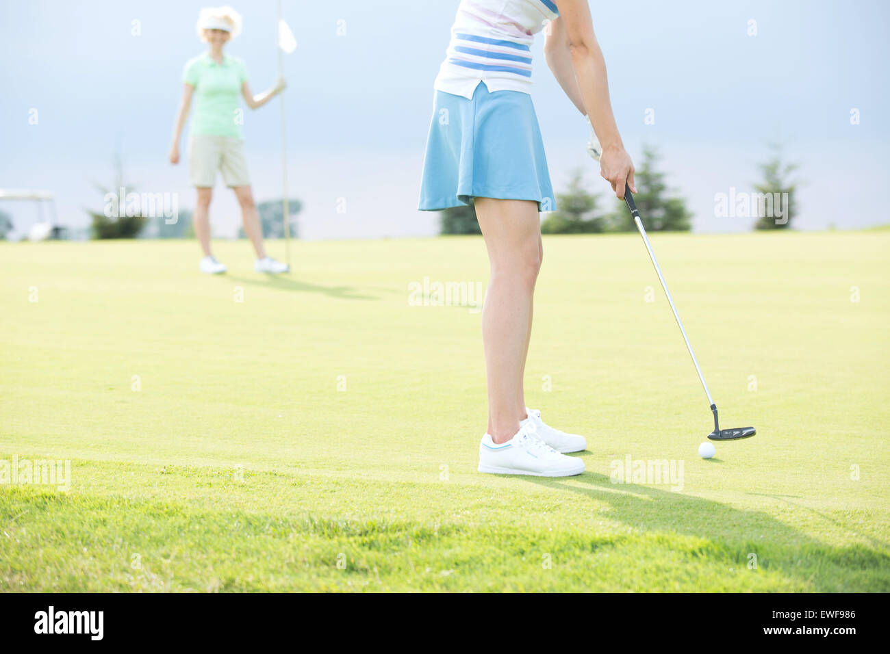 Sezione bassa della donna che gioca a golf con amico femmina Foto Stock