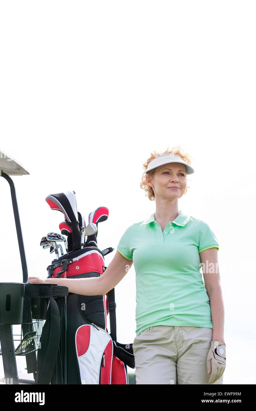 Basso angolo vista del golfista sorridente in piedi contro il cielo chiaro Foto Stock