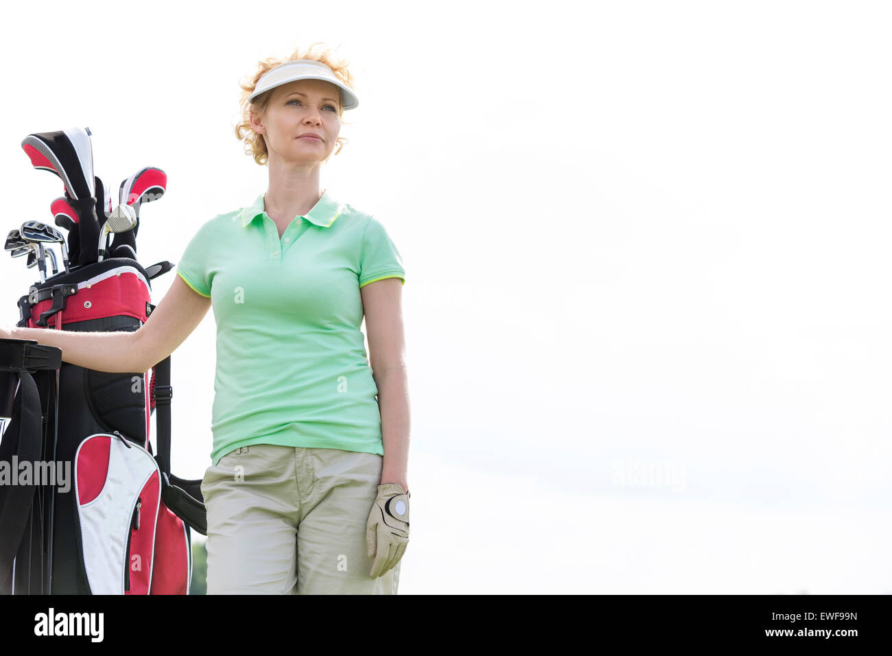 Basso angolo di vista fiducioso golfista femmina in piedi contro il cielo chiaro Foto Stock